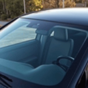 Luxury car receiving ceramic tint application, focusing on the precision of the installation technicians hands. The car is sleek, modern, and high-end, reflecting the premium service.